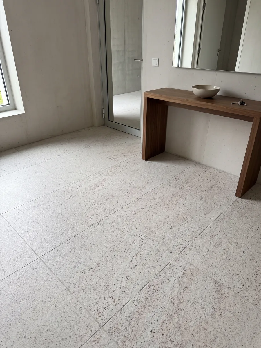 Entryway floor in large slabs of white Branco Siena granite with natural light: white with fine pink and gray speckling
