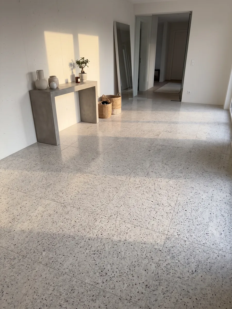 Entryway floor in large Blanco Dallas granite slabs with natural light: creamy white with fine gray speckling and small burgundy dots