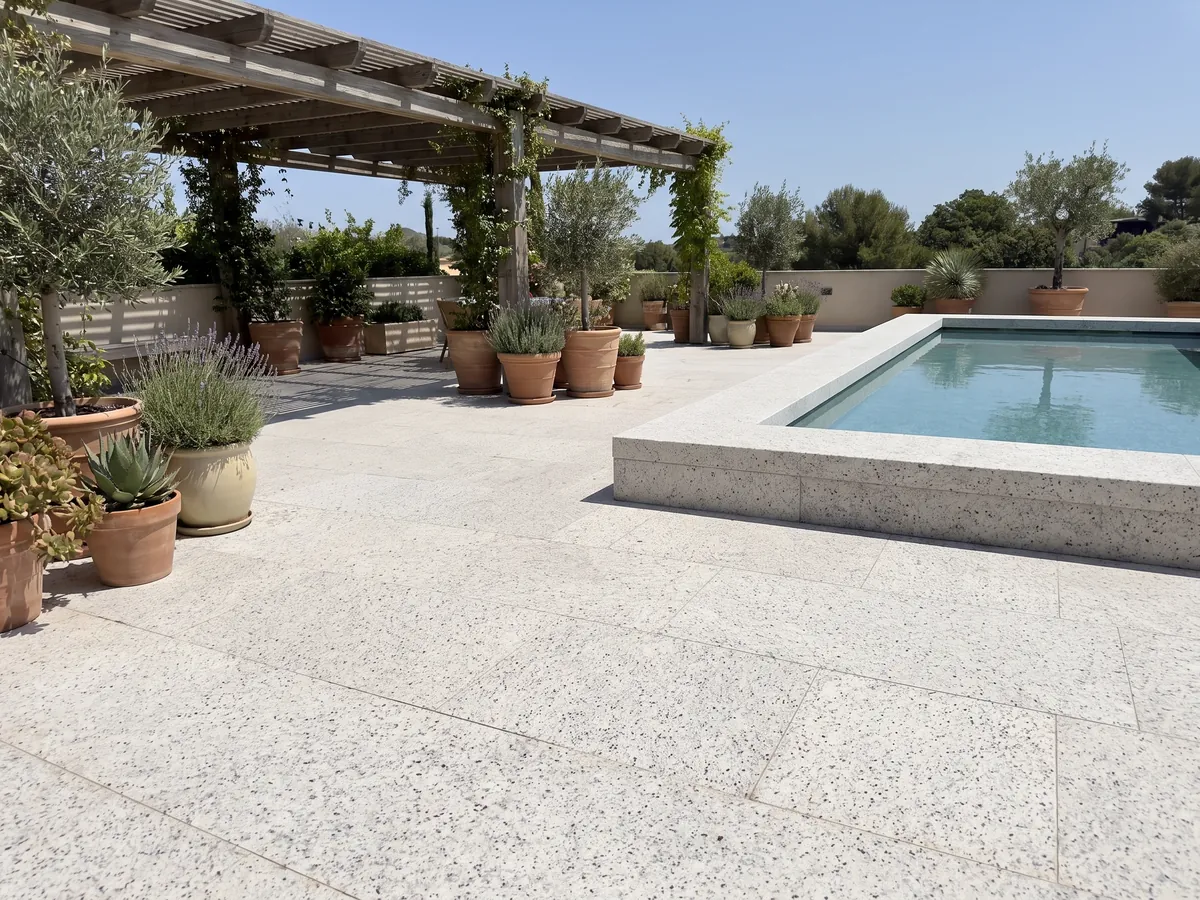 Terrace floor and pool coping in Blanco Dallas granite with planters: creamy white with fine gray speckling and small burgundy dots