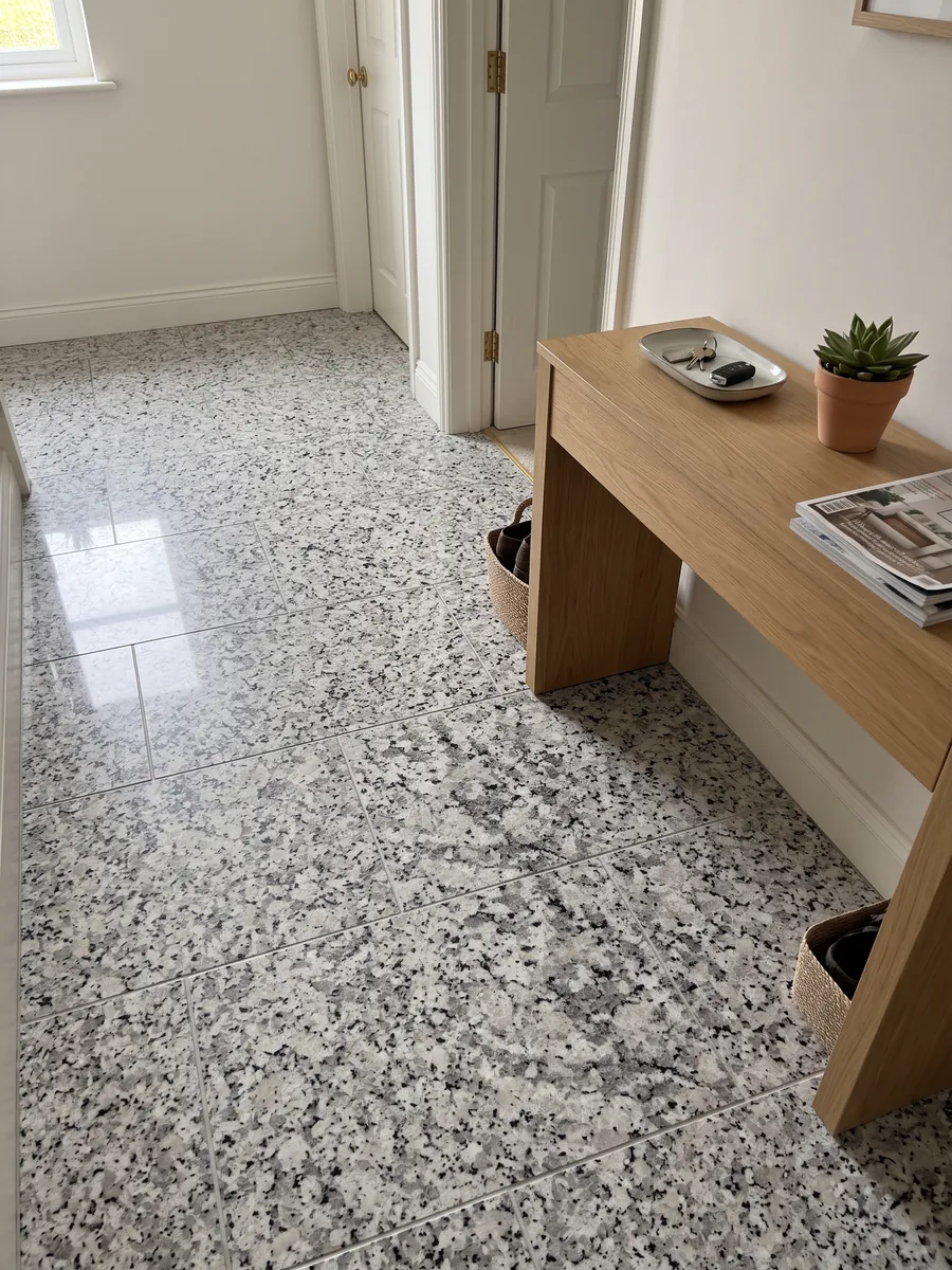 Entryway floor in large white Bianco Sardo granite slabs with natural light: coarse-grained white with gray and black crystals