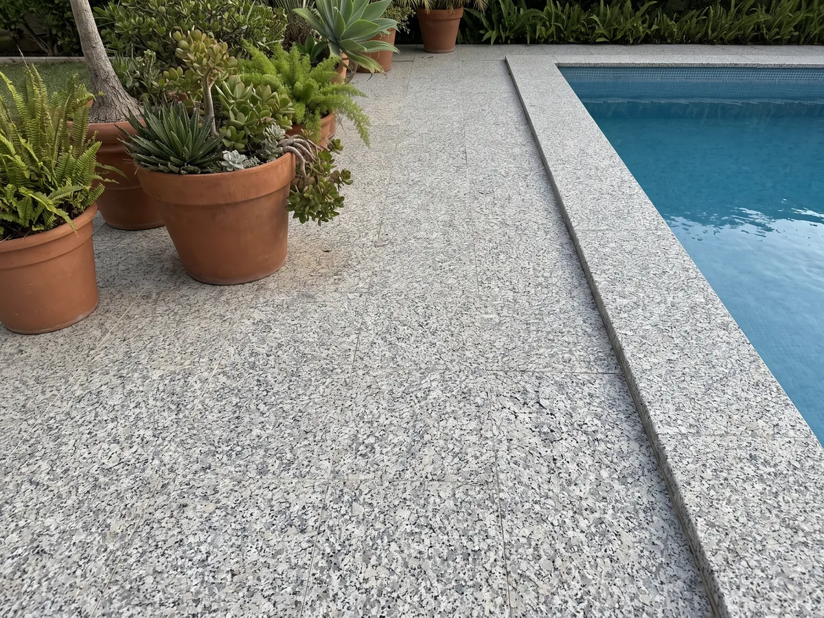 Terrace floor and pool coping in white Bianco Sardo granite with planters: coarse-grained white with gray and black crystals