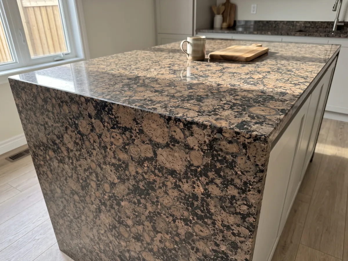 Kitchen island with a Baltic Brown granite countertop and a straight edge in a natural-light kitchen: round brown ringed grains on a black speckled background