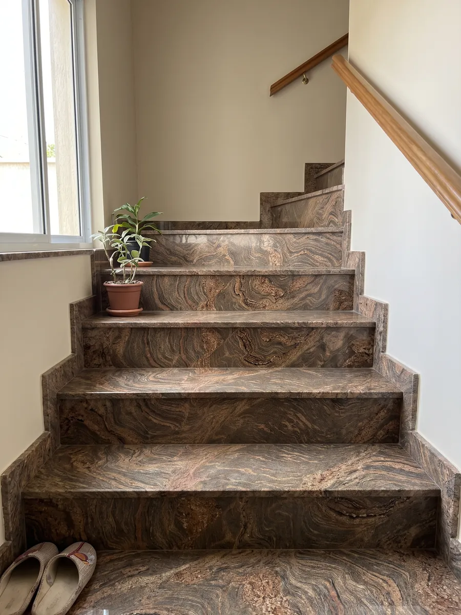 Interior staircase with Juparana Dourado granite steps and a handrail: ocher brown with very busy reddish waves and swirls