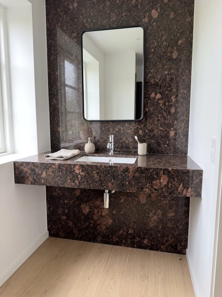 Bathroom vanity top and wall in Tan Brown granite with a white sink and chrome fixtures: chocolate brown with large copper patches and black dots