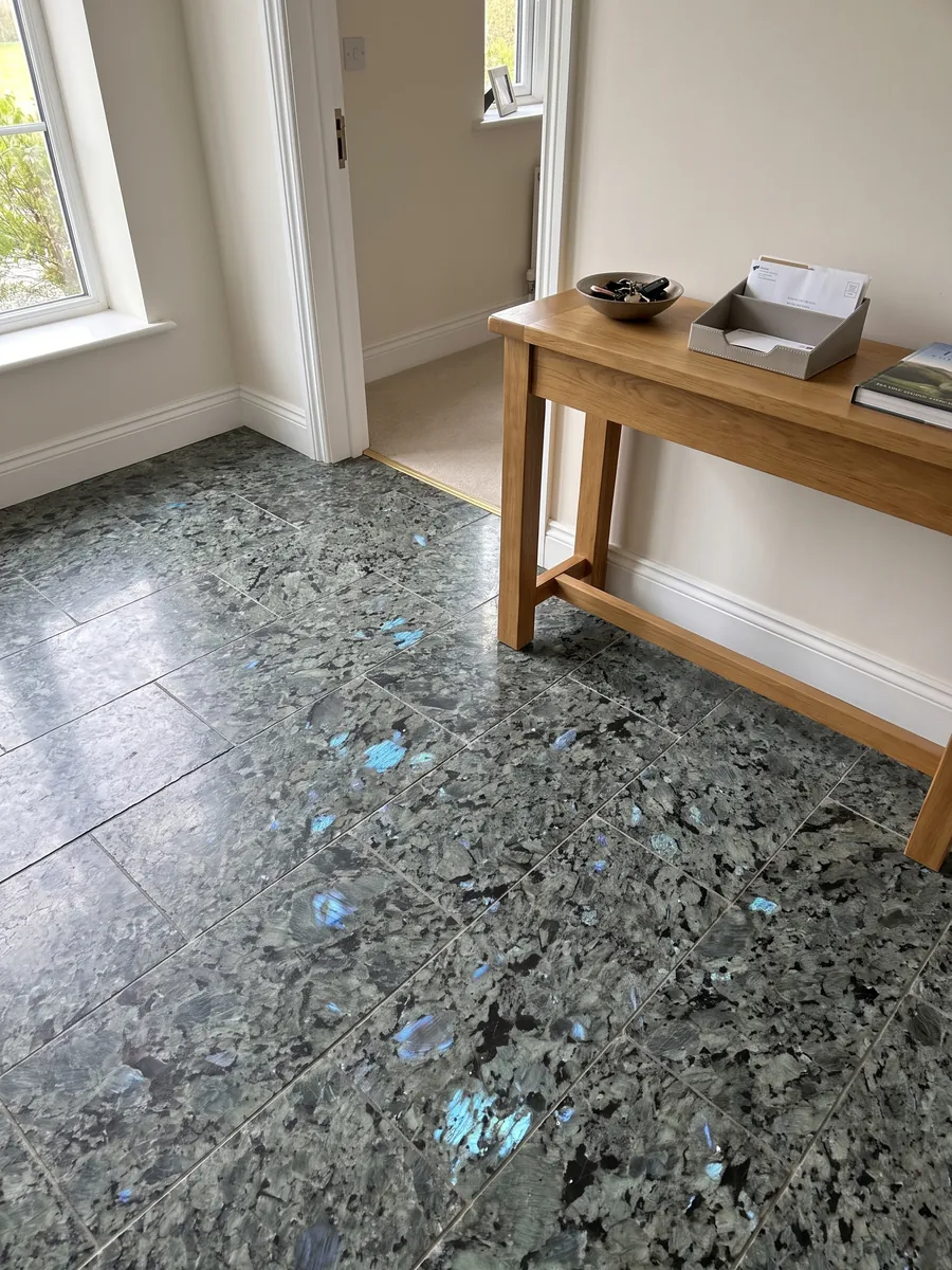 Entryway floor in large slabs of Labradorite granite with natural light: large greenish-gray crystals with iridescent blue flashes