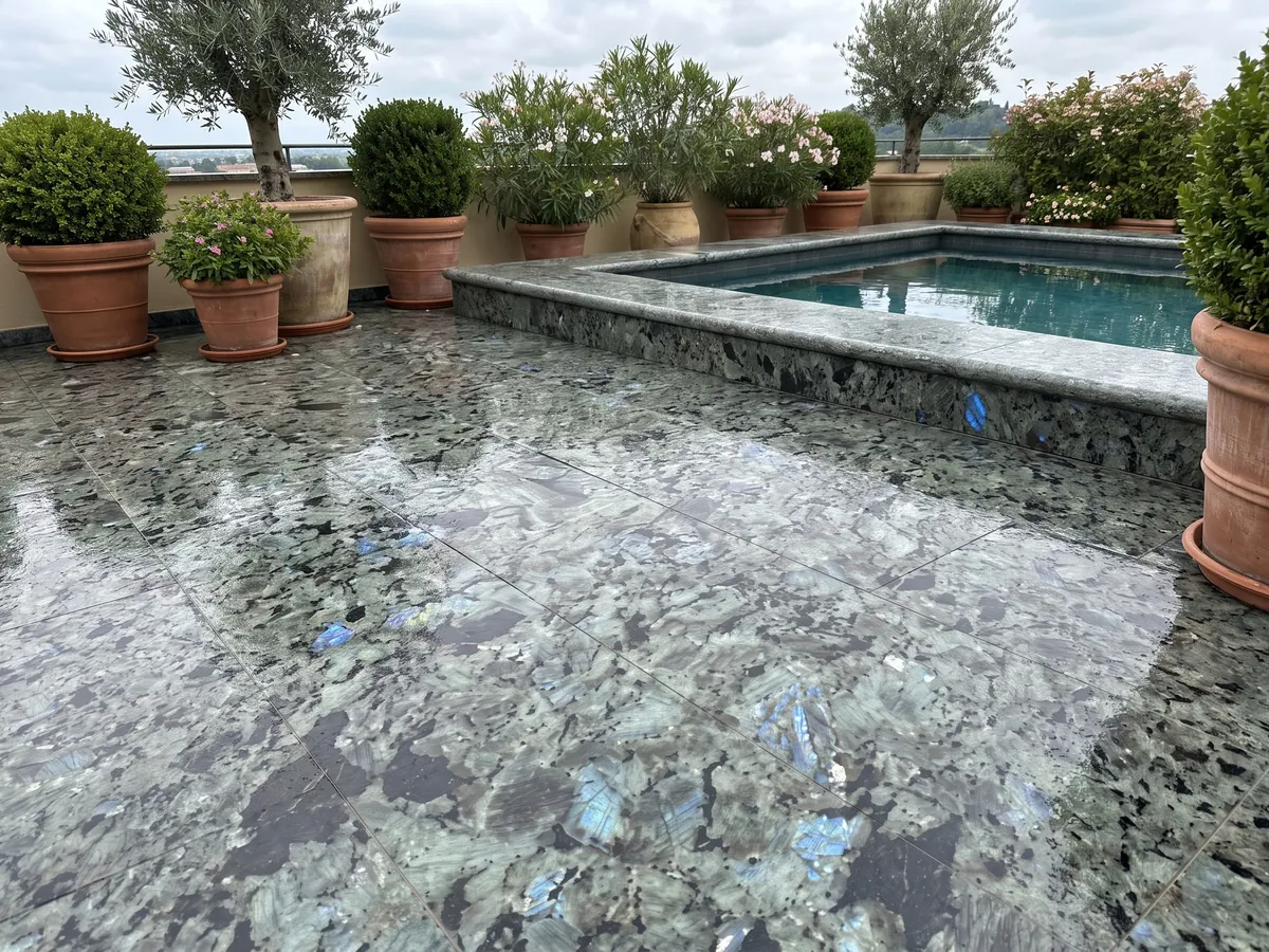 Terrace floor and pool coping in Labradorite granite with planters: large greenish-gray crystals with iridescent blue flashes