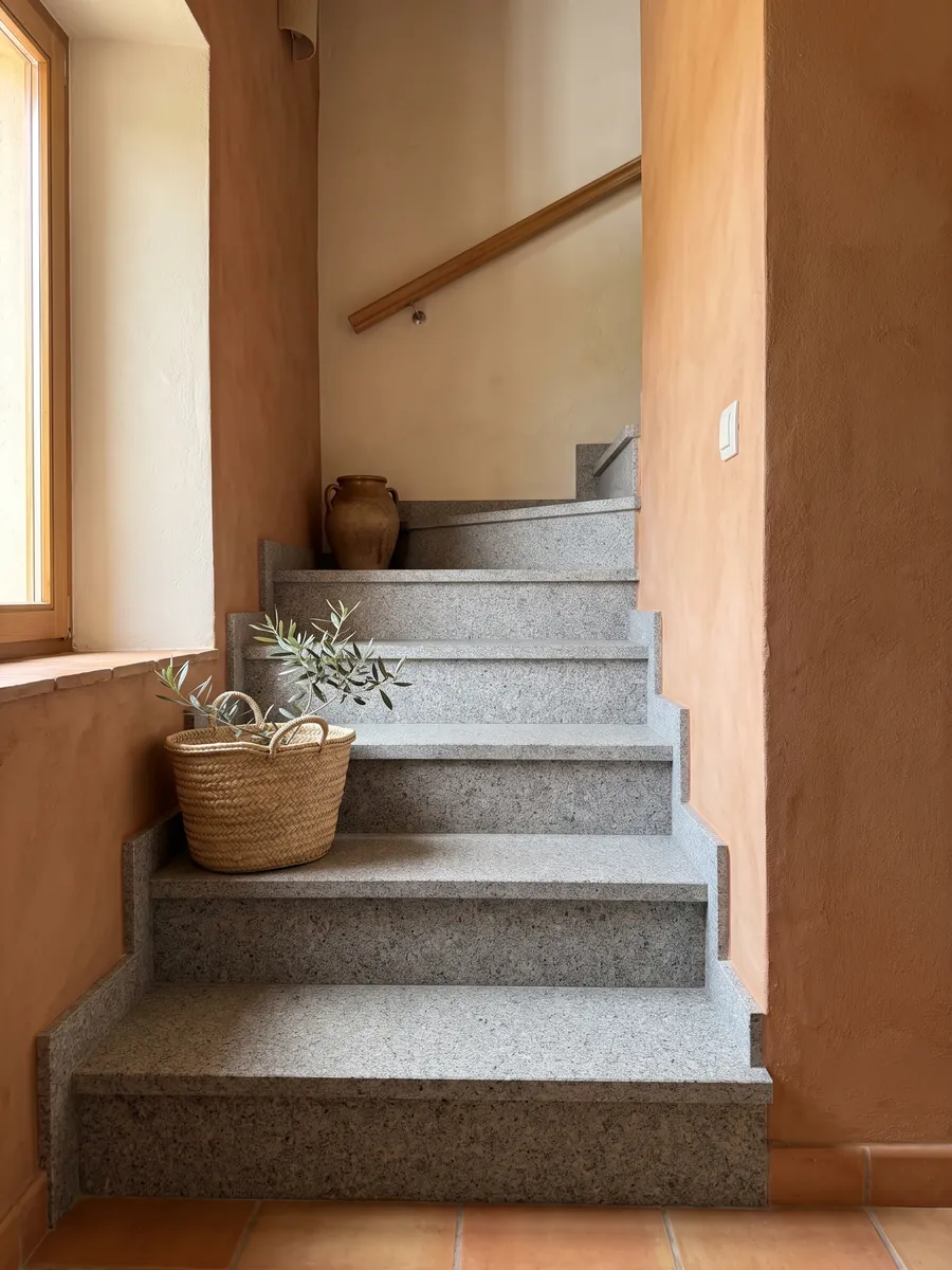 Indoor staircase with Gris Mara granite steps and a handrail: neutral gray with fine white and black grain spread evenly