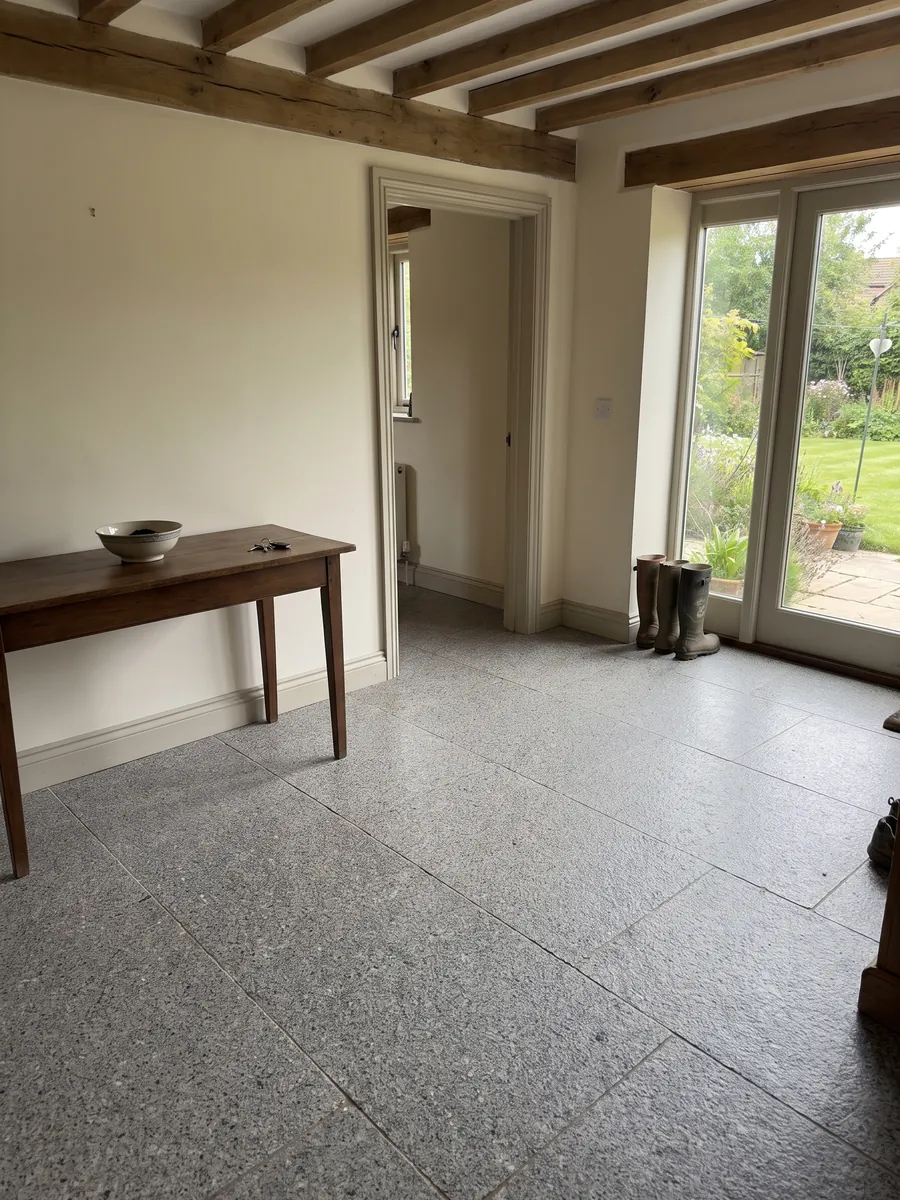 Entryway floor in large Gris Mara granite slabs with natural light: neutral gray with fine white and black grain spread evenly