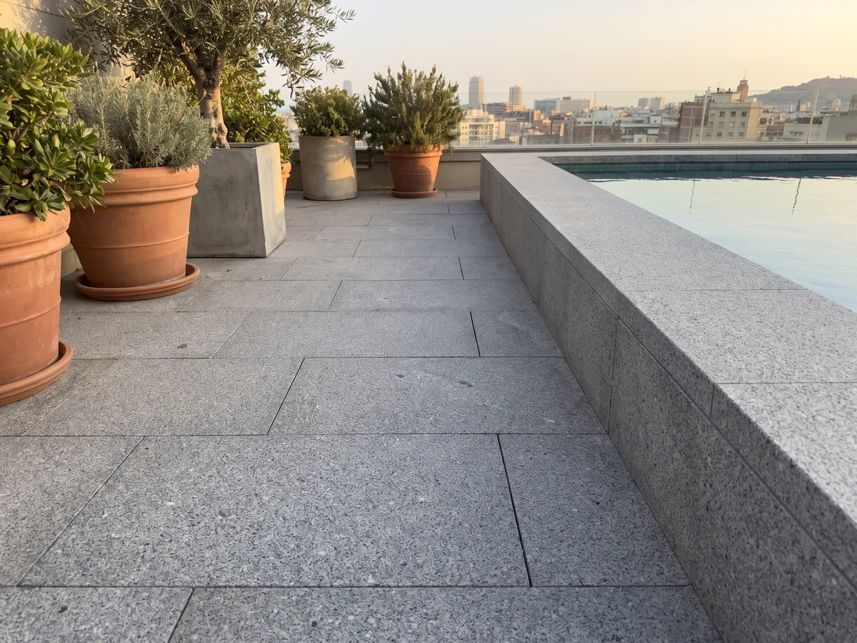 Terrace floor and pool coping in Gris Mara granite with planters: neutral gray with fine white and black grain spread evenly