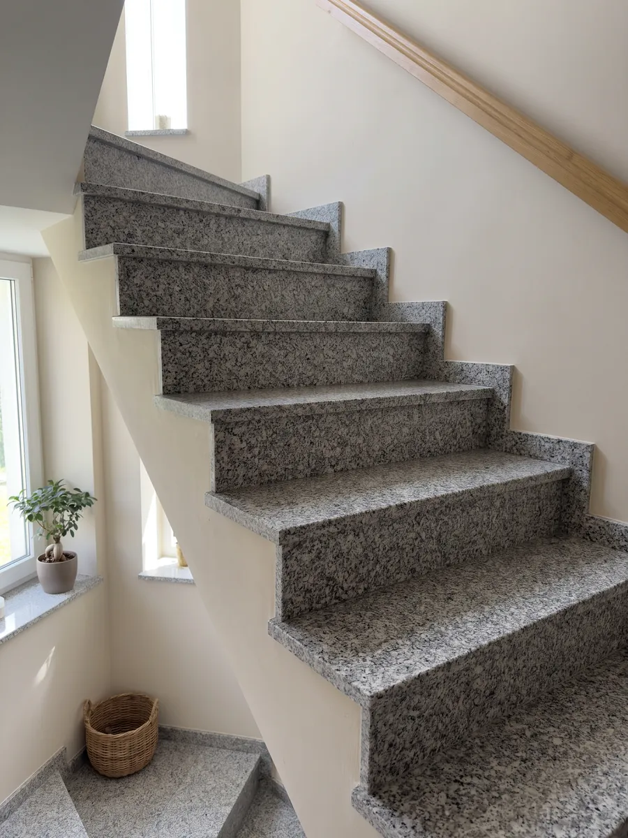 Interior staircase with Sardo Grigio granite steps and a handrail: light gray salt and pepper with a medium grain