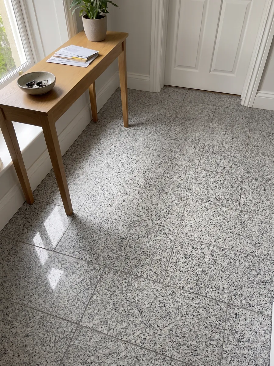 Entryway floor in large Sardo Grigio granite slabs with natural light: light gray salt and pepper with a medium grain