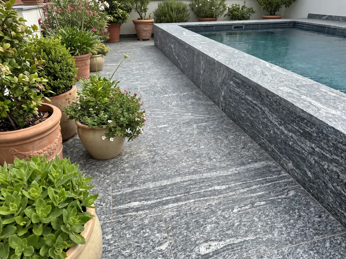 Terrace floor and pool coping in Serizzo granite with planters: dark gray with elongated horizontal white streaks