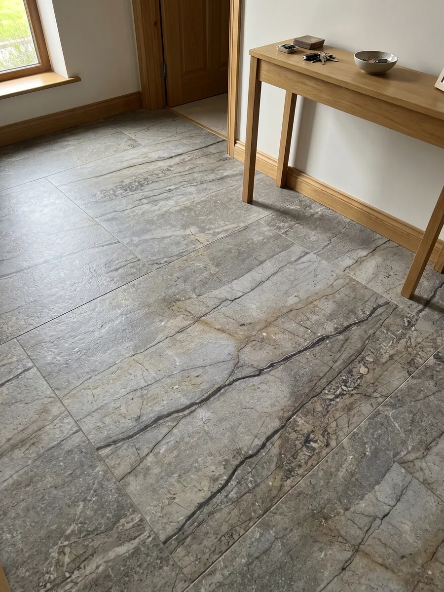Entryway floor in large Silver Roots granite slabs with natural light: taupe gray with horizontal dark veins and a natural stone look