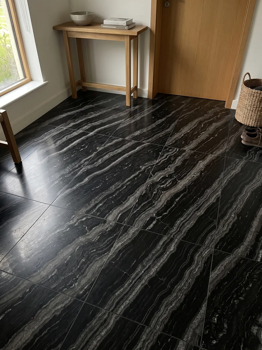 Entryway floor in large slabs of black Agata Black granite with natural light: black with parallel wavy silver-gray bands set on the diagonal