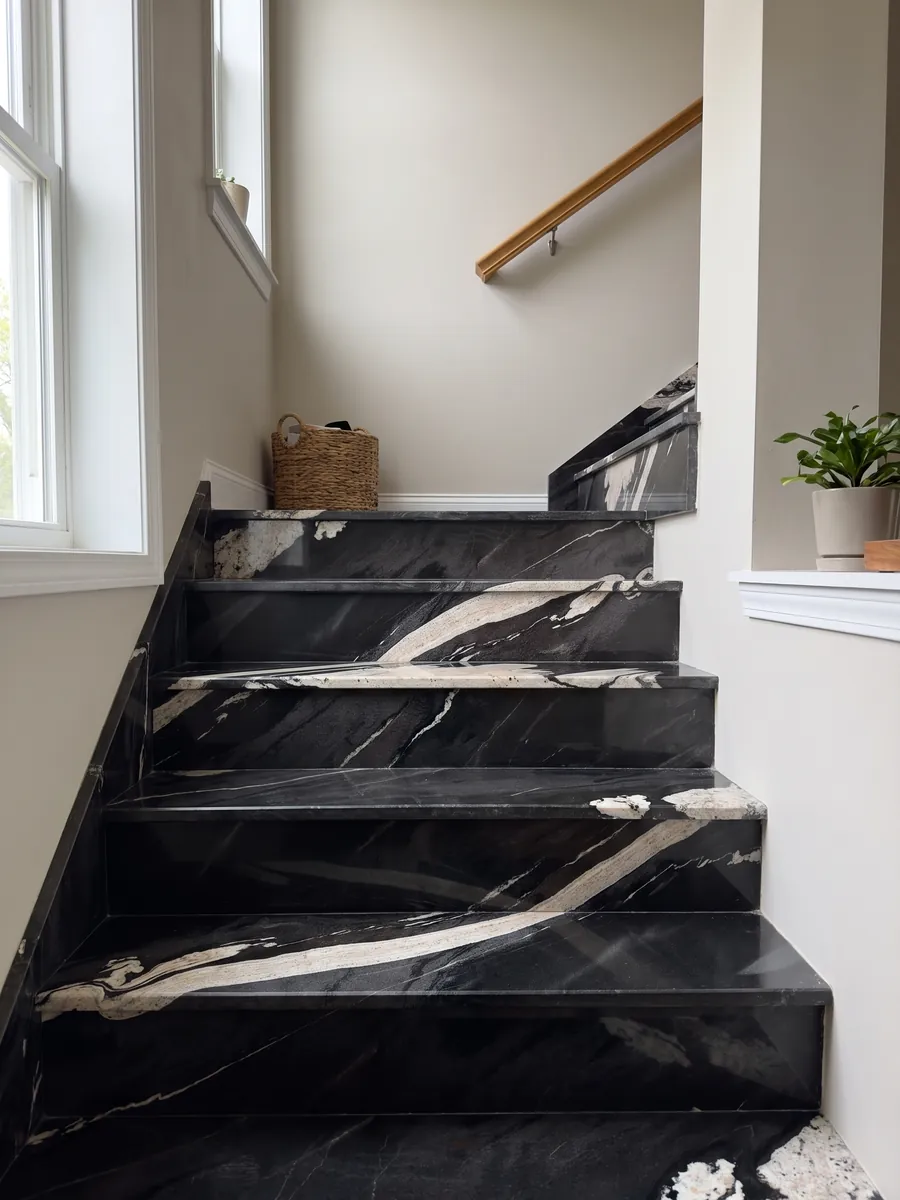 Interior staircase with black Copacabana granite steps and a handrail: black with a wavy cream band crossing on the diagonal