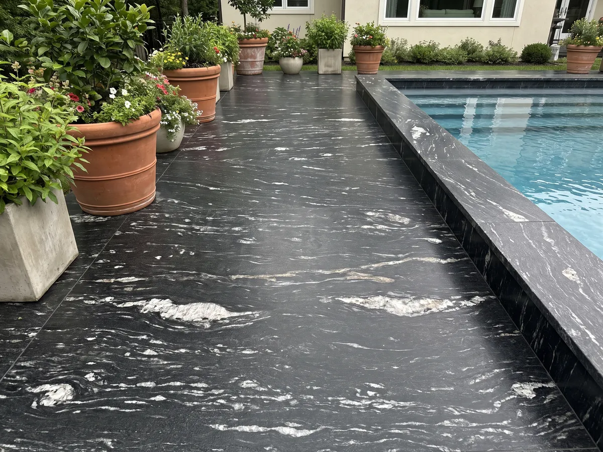 Terrace floor and pool coping in Cosmic Black granite with planters: black with horizontal wavy white veining
