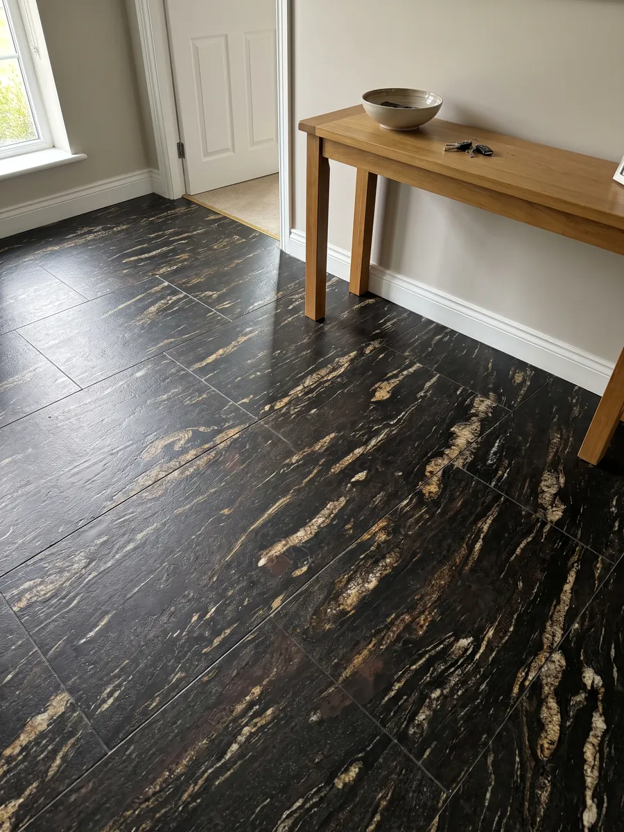Entryway floor in large black Matrix granite slabs with natural light: black with elongated golden streaks on the diagonal