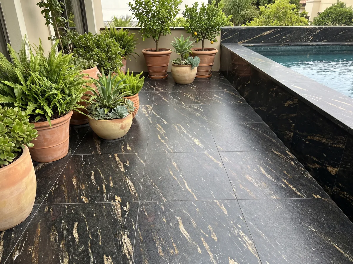 Terrace floor and pool coping in black Matrix granite with planters: black with elongated golden streaks on the diagonal