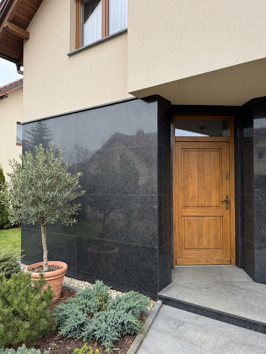 House facade clad in Nero Africa black granite next to a wood door: uniform fine-grained black with a light gray speckle