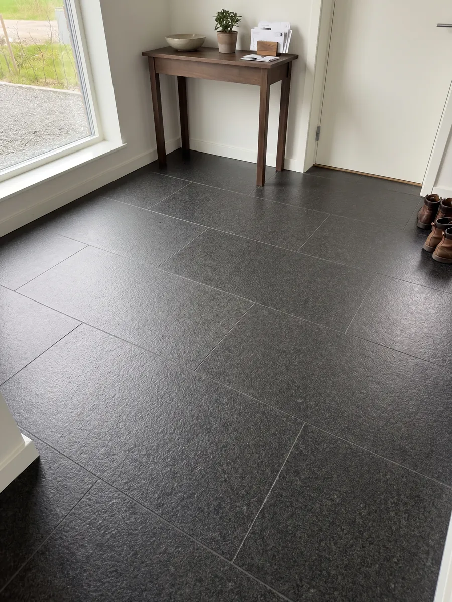 Entryway floor in large Nero Africa black granite slabs with natural light: uniform fine-grained black with a light gray speckle