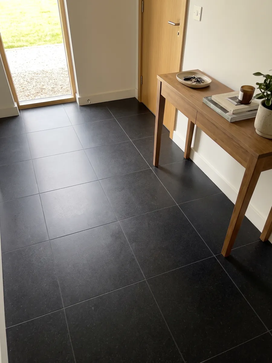 Entryway floor in large Nero Assoluto black granite slabs with natural light: uniform black with no pattern