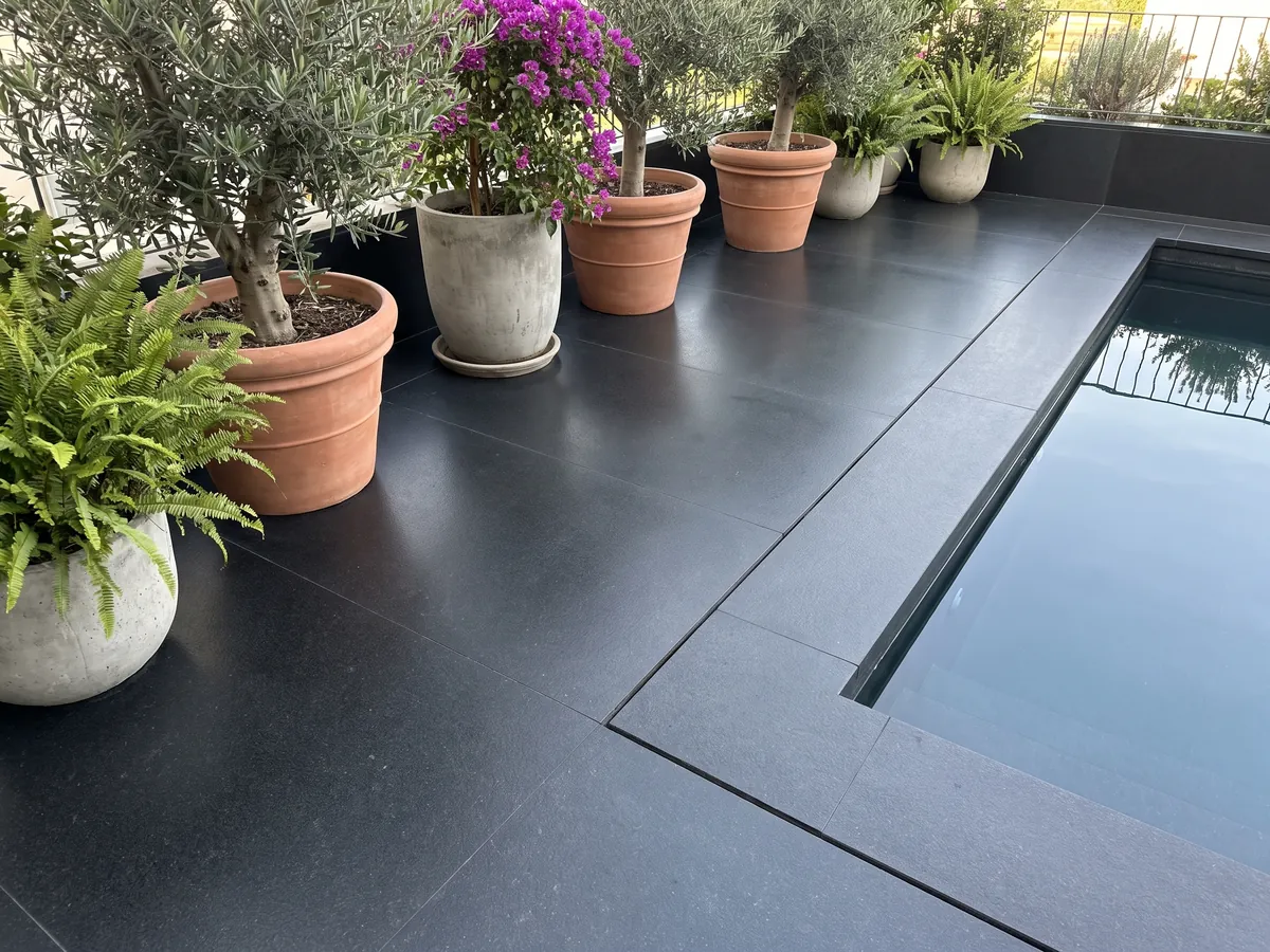 Terrace floor and pool coping in Nero Assoluto black granite with planters: uniform black with no pattern