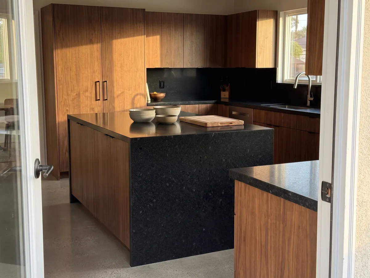 Kitchen island with a Negro San Gabriel granite countertop and a straight edge in a kitchen with natural light: deep black, medium grain, with dark gray speckles visible up close