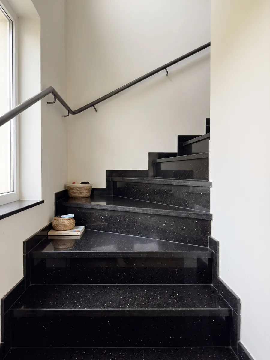 Interior staircase with black Star Galaxy granite steps and a handrail: black with small shining gold flecks