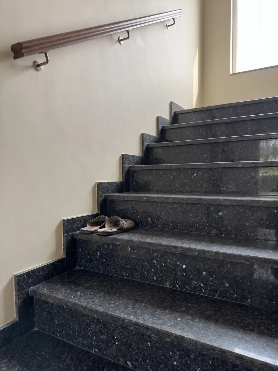Interior staircase with black Stargate granite steps and a handrail: granular anthracite gray with gray and violet crystals