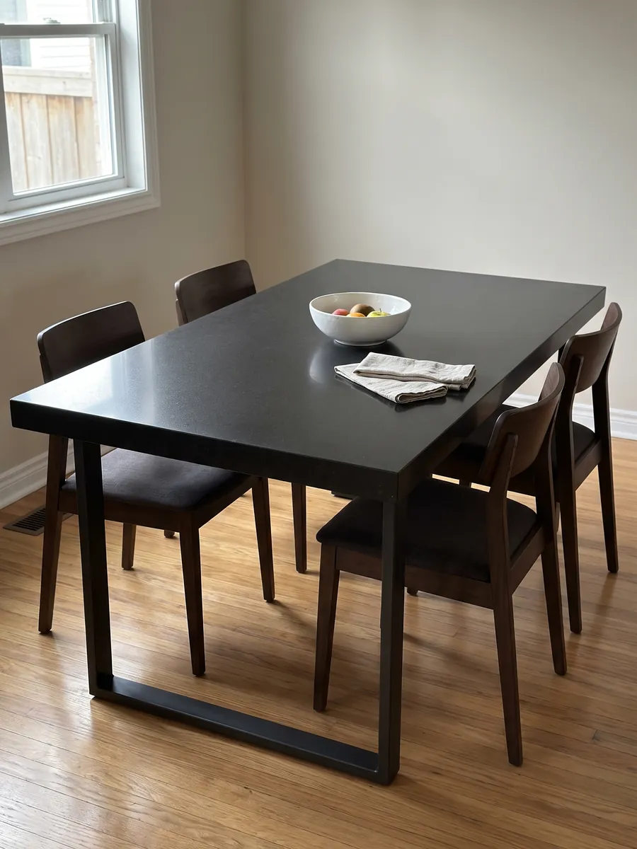 Dining table with a Titanium Black granite top on a steel base: an almost flat, uniform black with an extremely fine grain you only notice up close