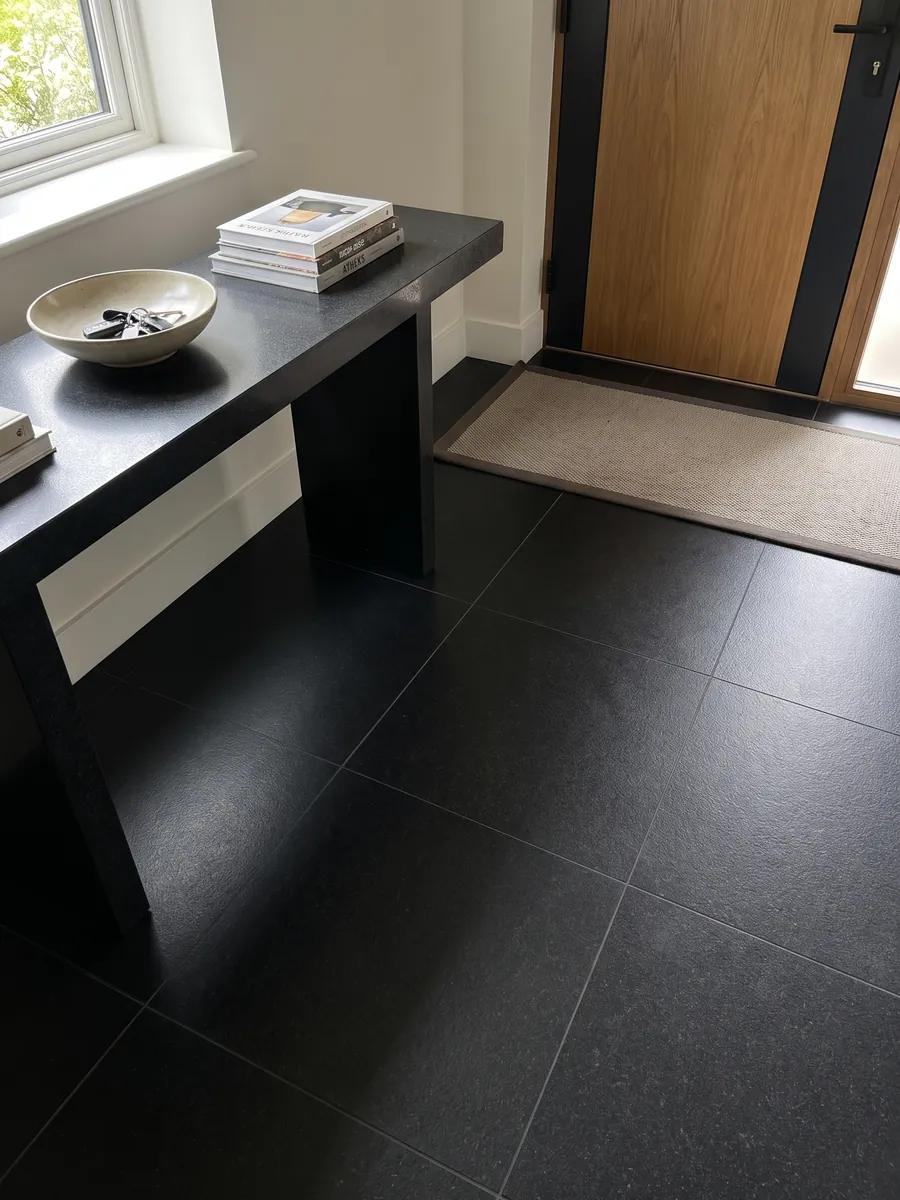 Entryway floor in large slabs of Titanium Black granite with natural light: an almost flat, uniform black with an extremely fine grain you only notice up close