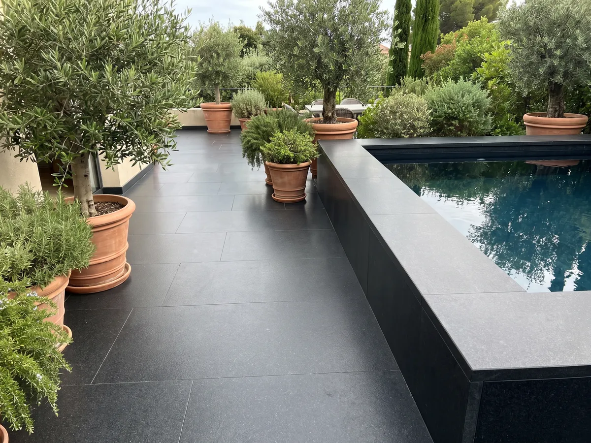 Terrace floor and pool coping in black Titanium Black granite with planters: an almost flat, uniform black with a very fine grain you only notice up close