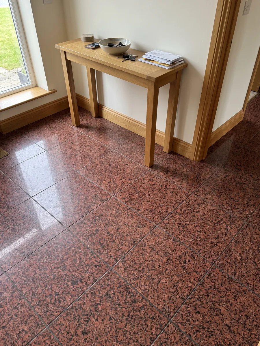 Entryway floor in large slabs of red Balmoral Red granite with natural light: deep granular red with black dots spread evenly