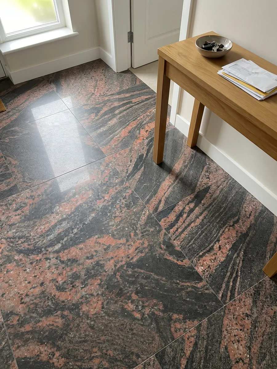 Entryway floor in large Indian Aurora red granite slabs with natural light: coral and dark gray waves running diagonally