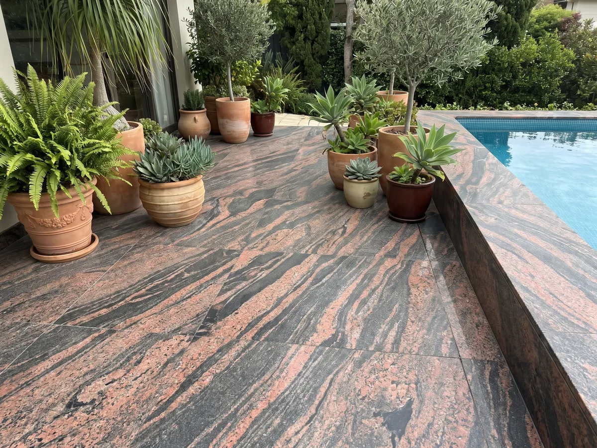 Terrace floor and pool coping in Indian Aurora red granite with planters: coral and dark gray waves running diagonally