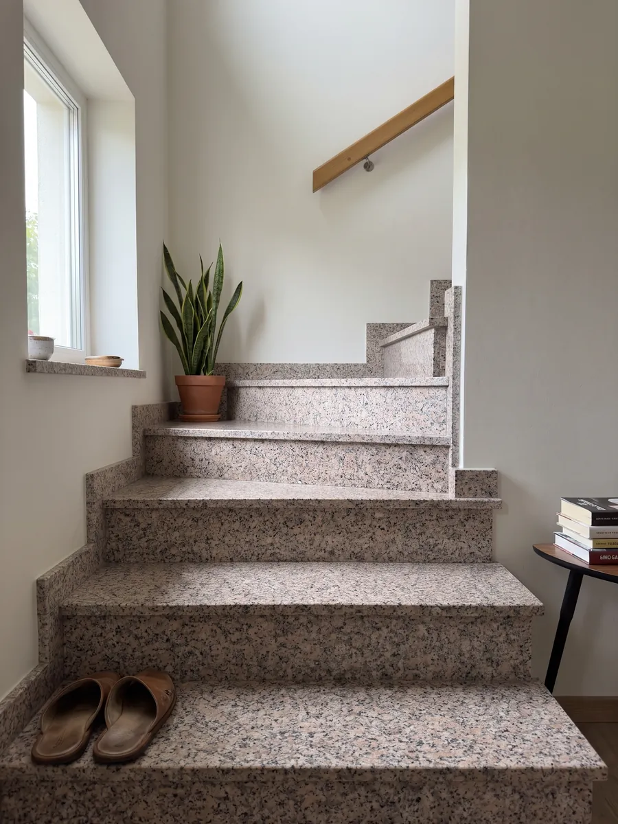 Interior staircase with Rosa Beta granite steps and a handrail: white grain with pale pink and black dots
