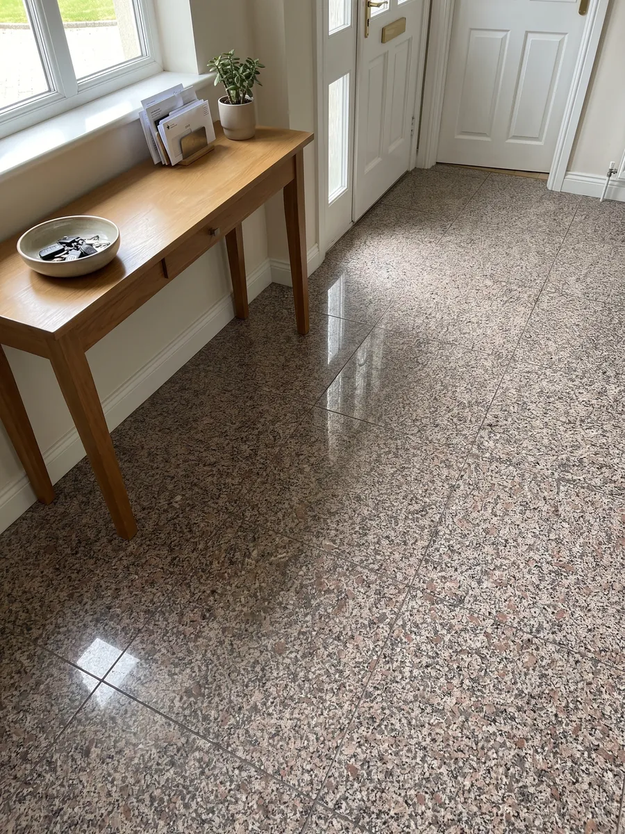 Entryway floor in large slabs of pink Limbara granite with natural light: pinkish-brown grain with white and black crystals