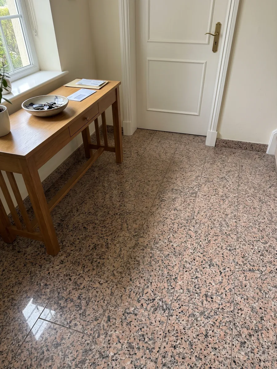 Entryway floor in large Rosa Porriño granite slabs with natural light: speckled salmon pink with black specks