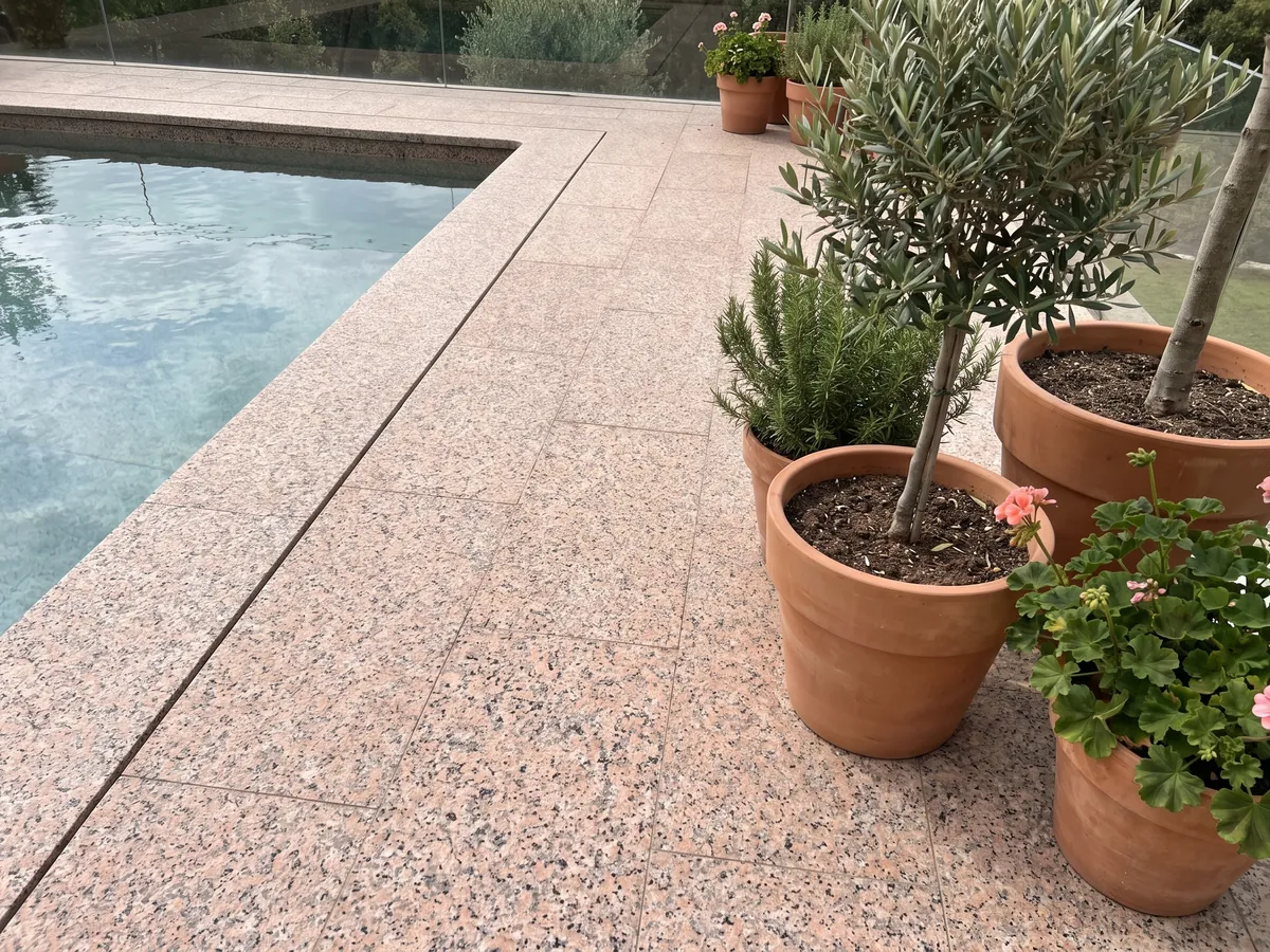 Terrace floor and pool coping in Rosa Porriño granite with planters: granular salmon pink with black speckles