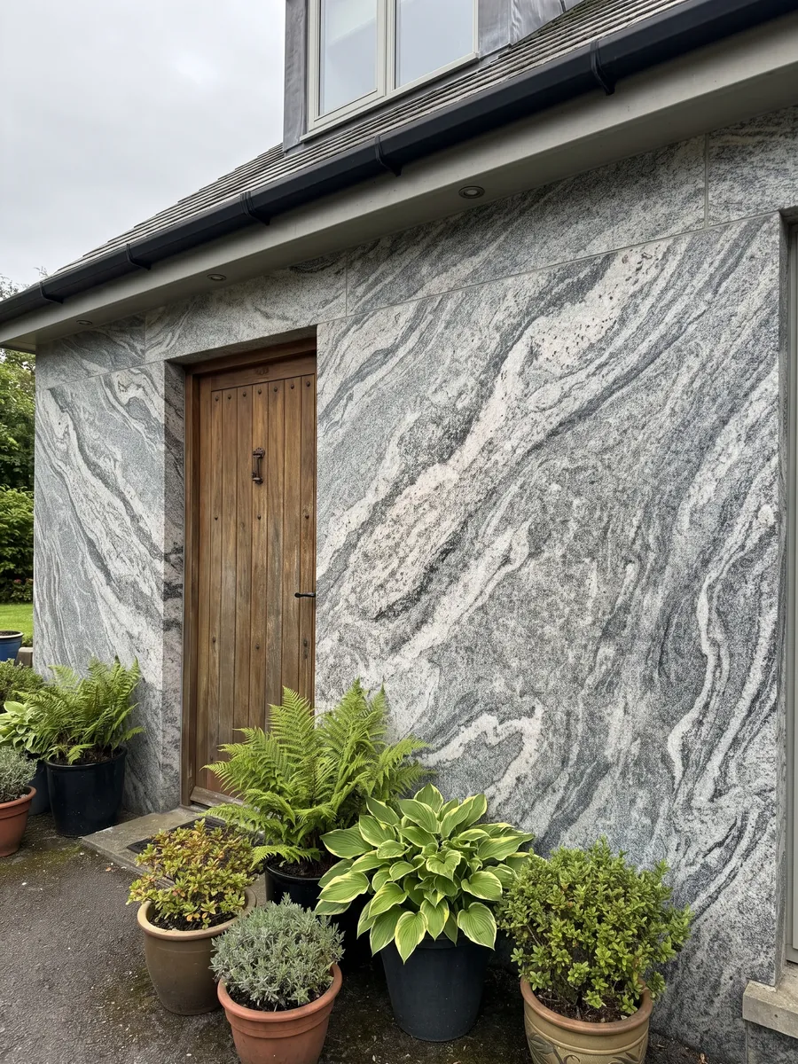House facade clad in Verde Marina granite next to a wood door: visible-grain white and grey wavy bands; the photo shows no green tones