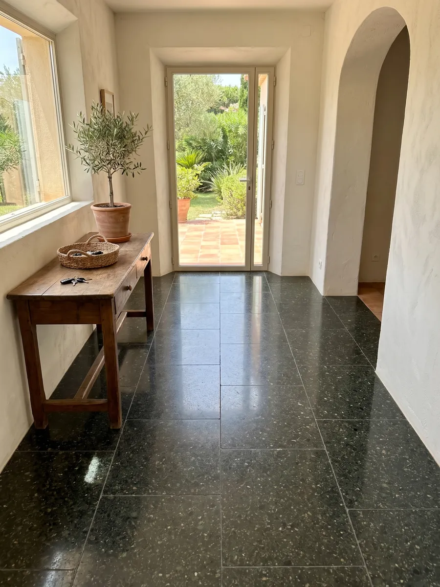 Entryway floor in large Verde Ubatuba granite slabs with natural light: a nearly black green with flashes of light green and gold