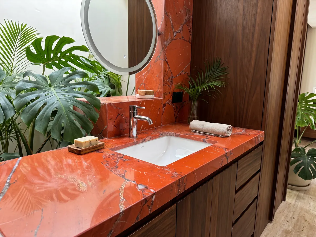 Vanity top and bathroom wall in Red Jasper with a white sink and chrome faucets: intense orange-red in large pieces with fine gray joints