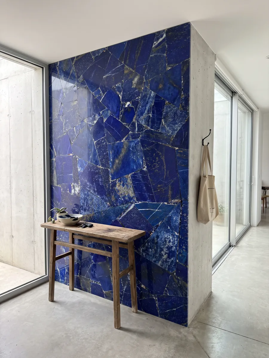 Entryway wall clad in lapis lazuli with a narrow console: intense ultramarine in angular pieces with white and golden flecks