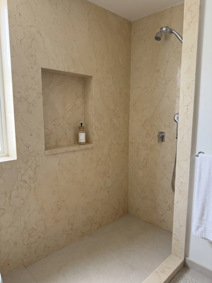 Shower clad in full slabs of Giallo Silvia Oro marble with a recessed niche: very uniform pale yellow with barely visible fine veining of light lines