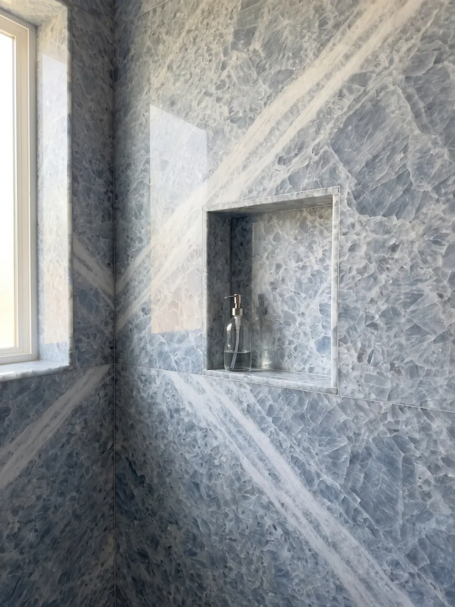Shower clad in full slabs of Azul Calcite marble with a recessed niche: thick grayish-blue crystals on white, with a whiter diagonal band