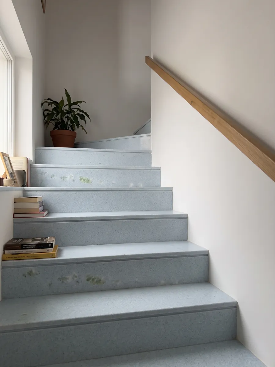 Interior staircase with Azul Cielo marble steps and a handrail: nearly uniform pale sky blue, fine-grained, with a green inclusion on the left