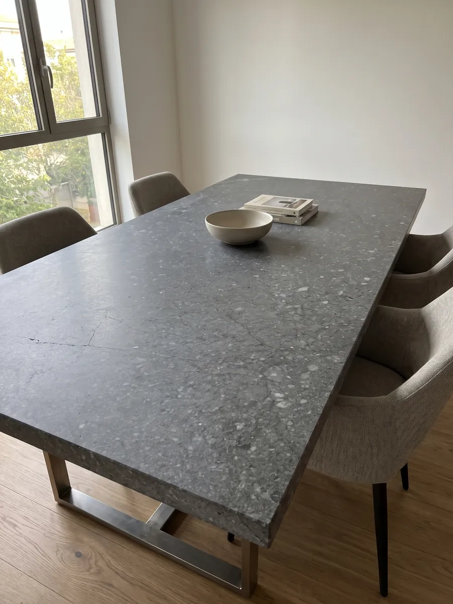 Dining table with a Blu Masaccio marble top on a steel base: uniform dark gray with small speckles and lighter gray fragments