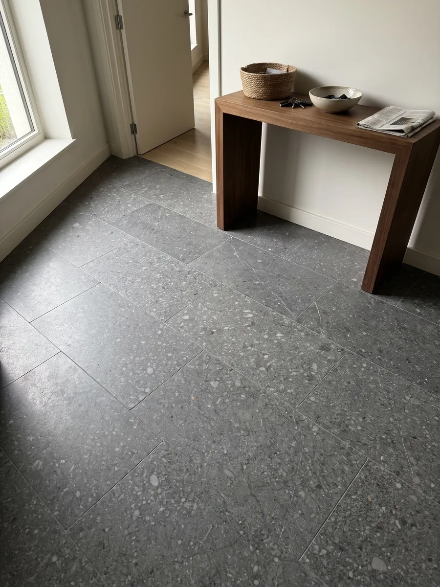 Entryway floor in large slabs of Blu Masaccio marble with natural light: uniform dark gray with small speckles and lighter gray fragments