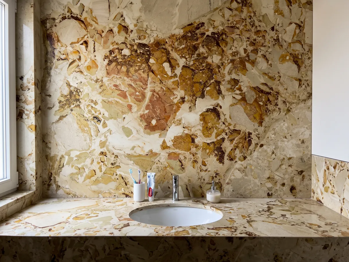 Vanity top and bathroom wall in beige Alma Fuoco marble with a white sink and chrome faucets: ocher and rust stains with crisp edges grouping in the upper central area