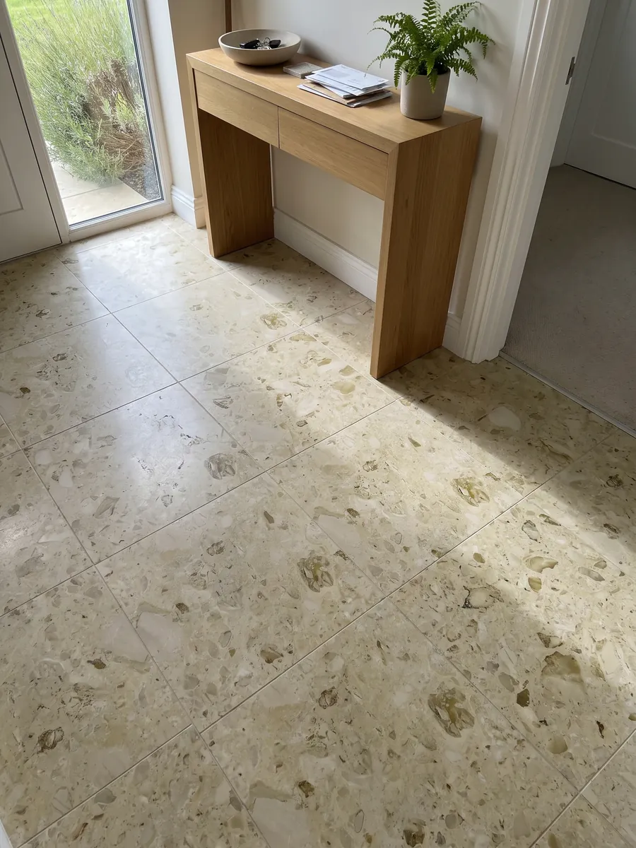 Entryway floor in large beige Alma marble slabs with natural light: a greenish cream background with soft, scattered olive fossil inclusions